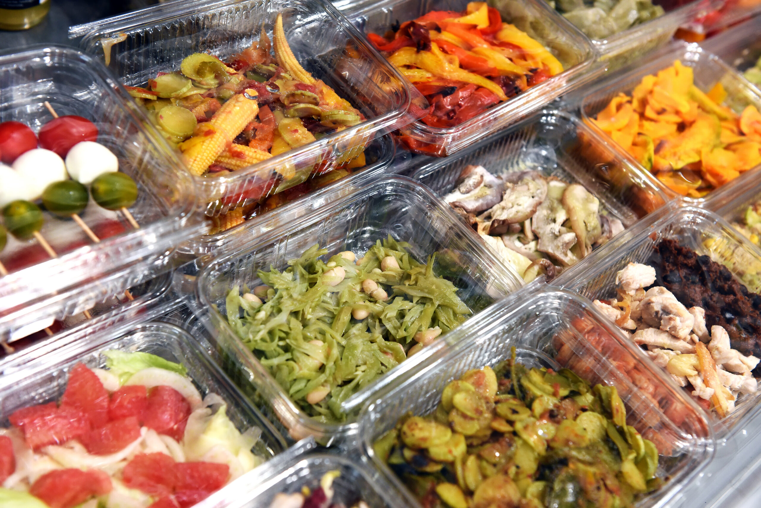 Ready to eat prepared food displayed in metal bins at a shop, restaurant or delicatessen for a buffet style meal